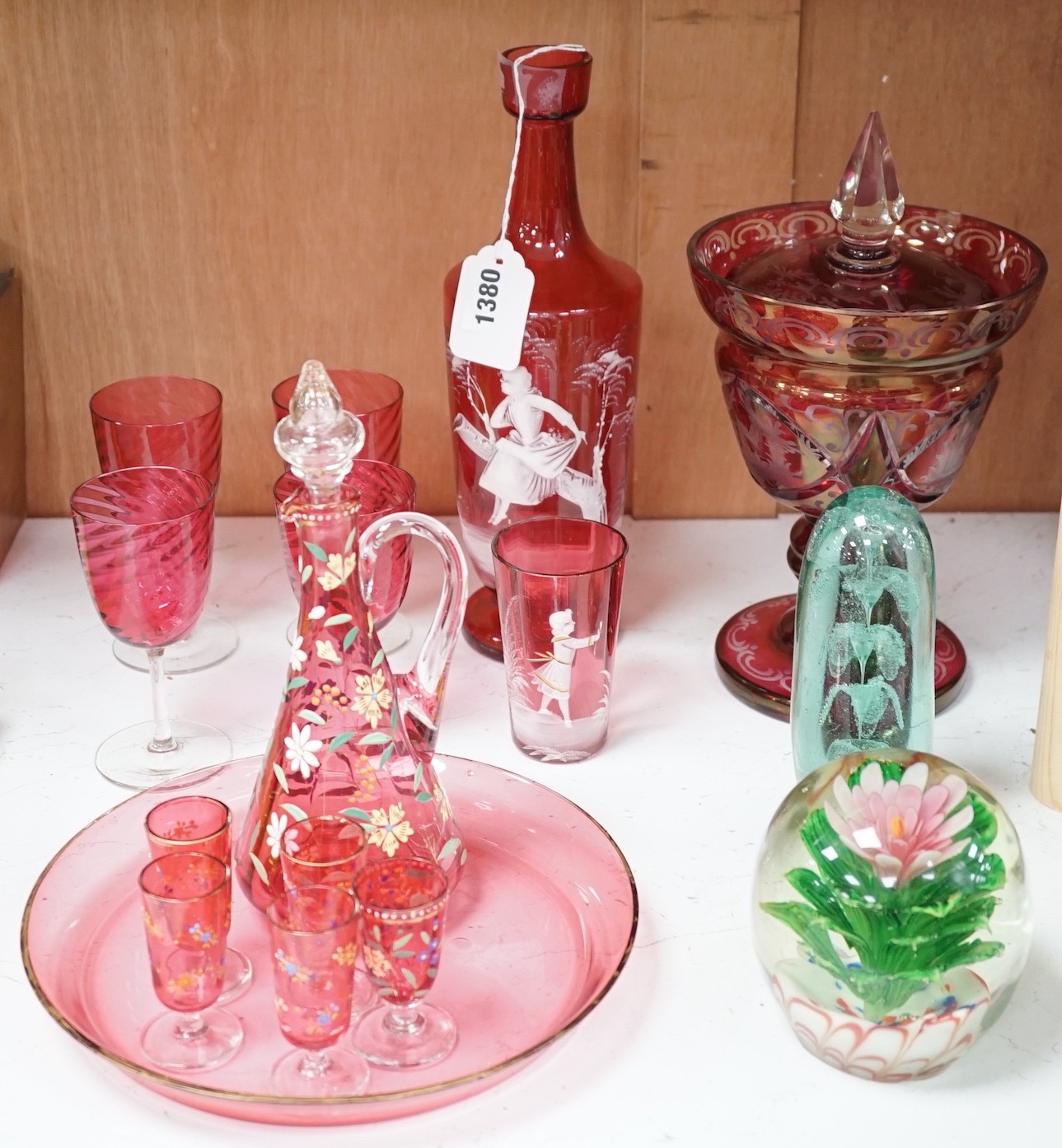A collection of cranberry glass, a dump paperweight, another and a sweetmeat jar, tallest 28.5 cm